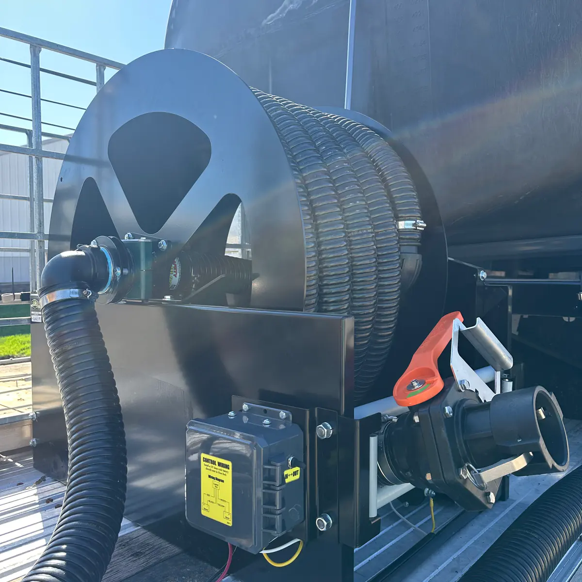 Close-up of a nurse trailer hose reel, ball valve and cam-lock plumbing manifold built by Dahl Farm Supply